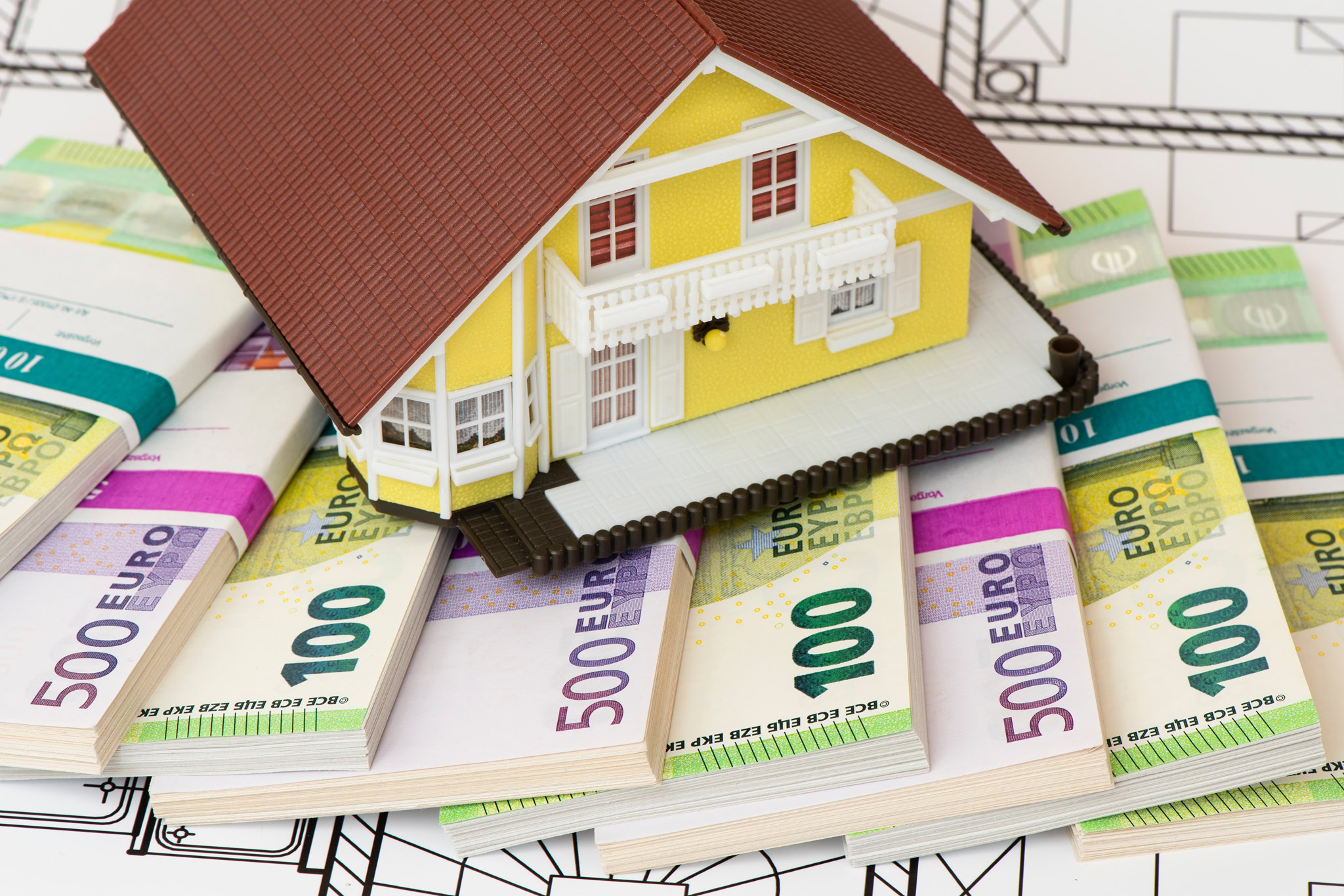 Modelhaus auf Geldscheinen als Symbol f&uuml;r die Grundschuld