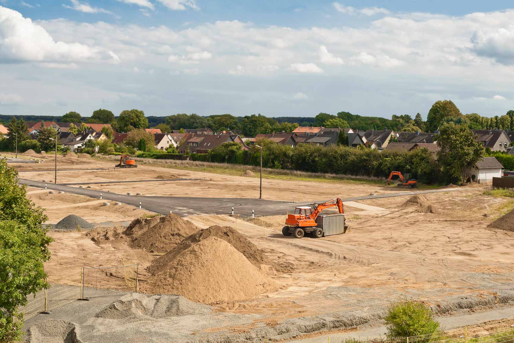 Gro&szlig;fl&auml;chiges Rohbauland mit Sand- und Erdh&uuml;geln, mehreren Baggern und neu angelegten Stra&szlig;en.